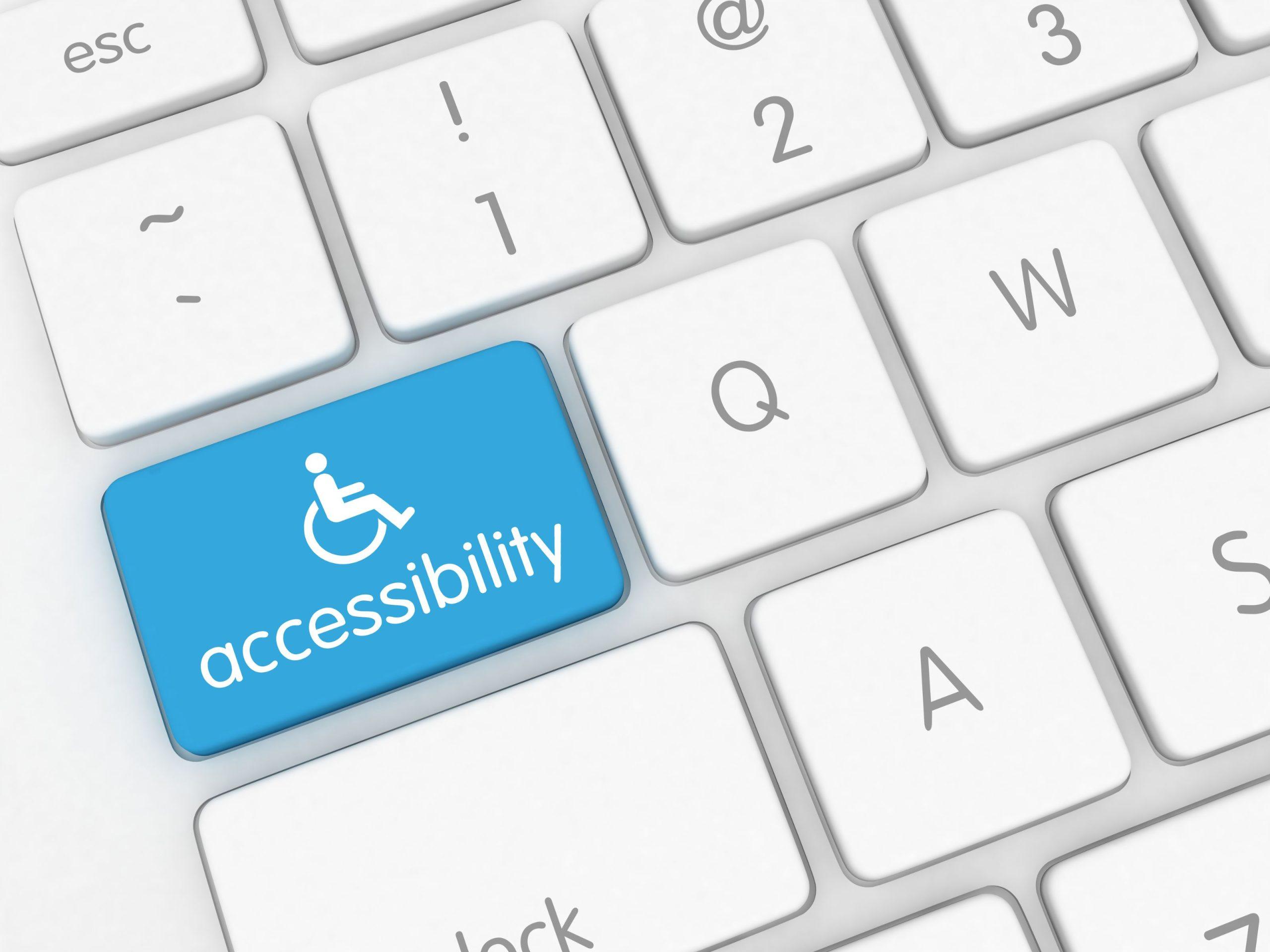 A white keyboard with a blue key labeled accessibility featuring a wheelchair icon, emphasizing inclusive design